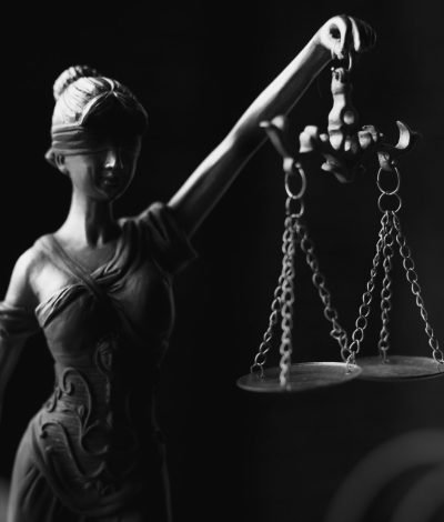 A close-up black and white photo of the Lady Justice figurine with scales.